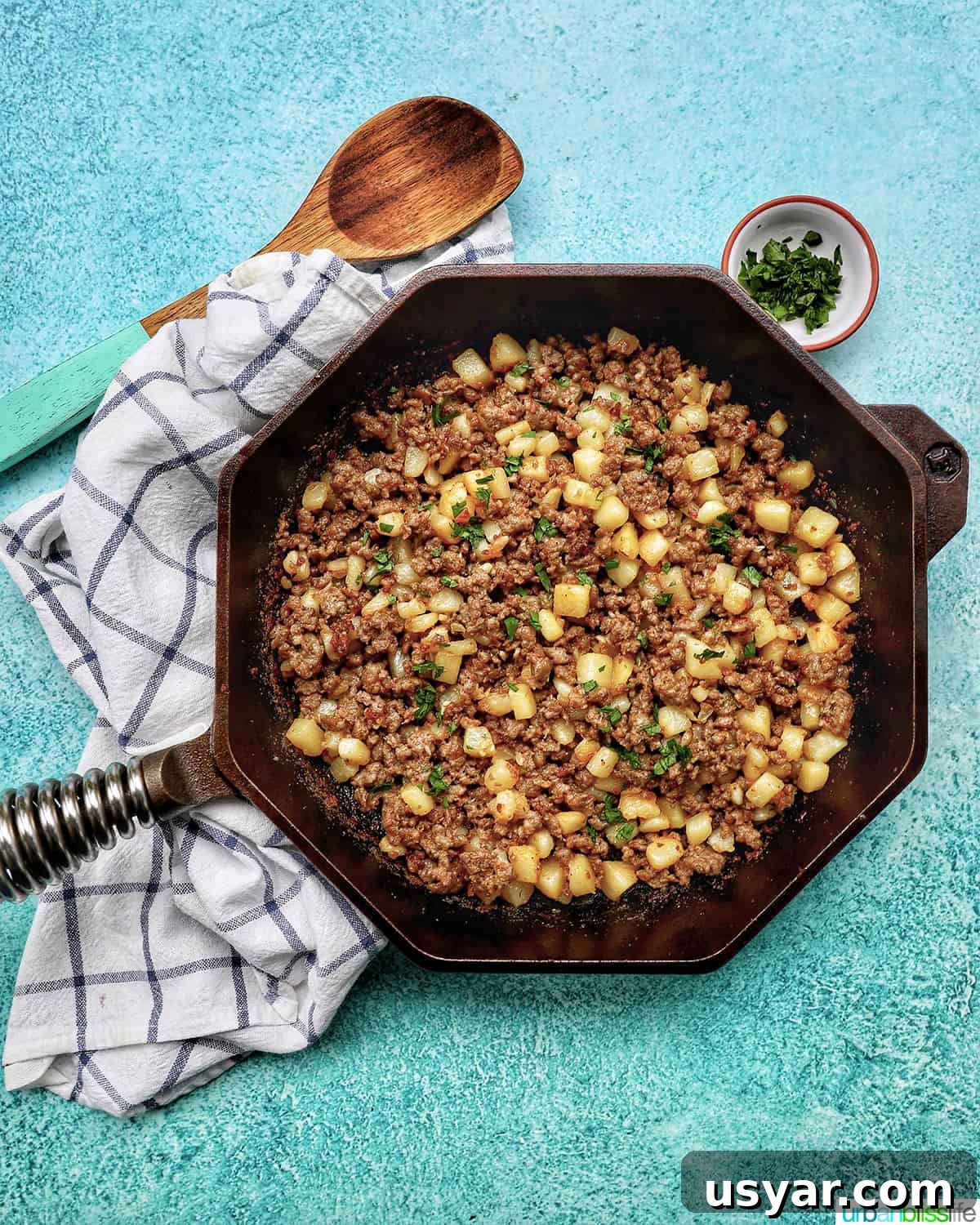 Breakfast Sausage and Potato Hash Recipe 21 Breakfast sausage potato hash in a skillet with a wooden spoon