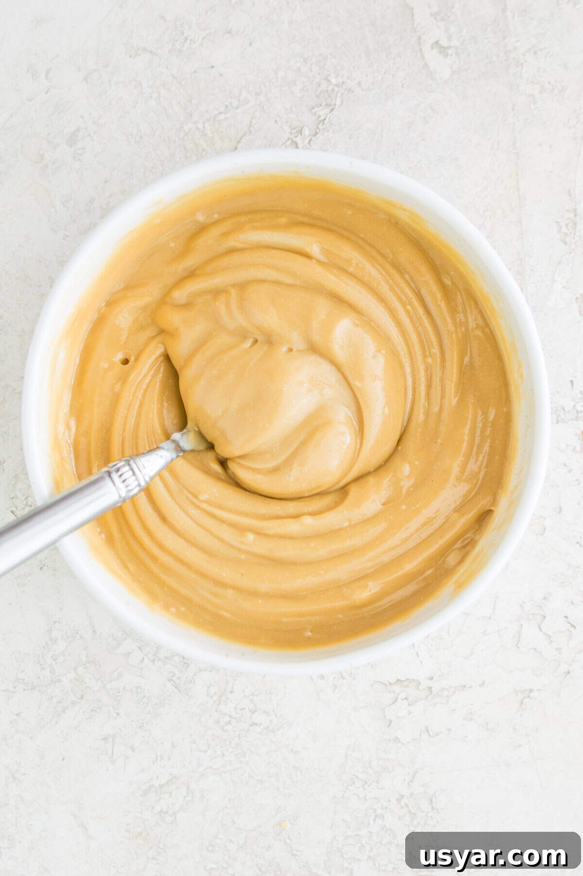 Gluten-Free Vegan and Paleo Apple Pie Bars 7 A caramel sauce in a bowl with a spoon in it.