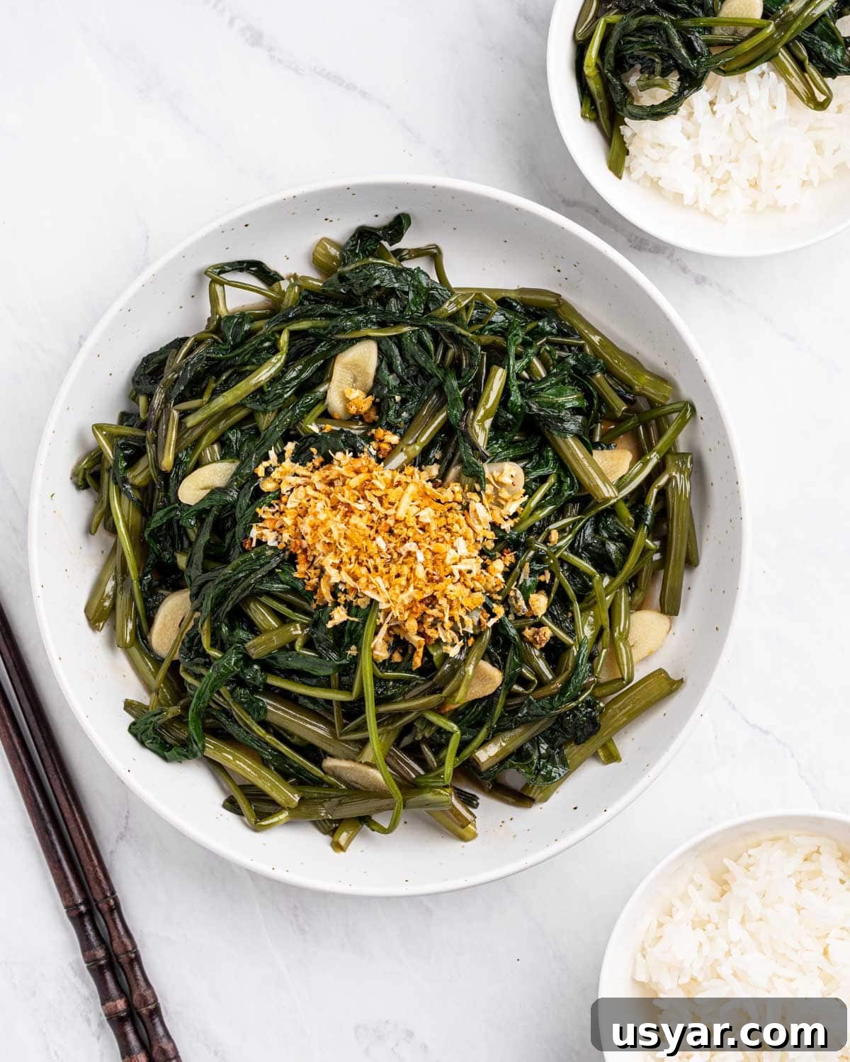 Vietnamese Garlic Water Spinach Stir Fry 11 Plate of morning glory stir fried with garlic surrounded by bowls of rice and a pair of chopsticks.