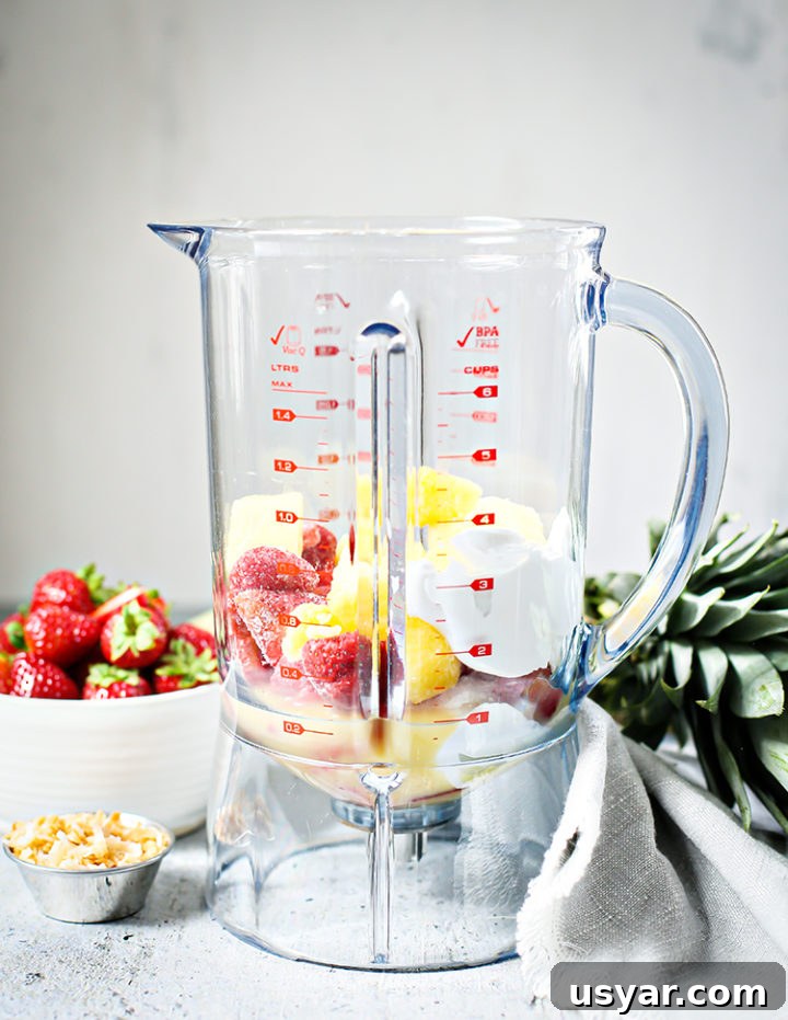 Strawberry Pineapple Smoothie Recipe 3 photo of ingredients for a Strawberry Pineapple Smoothie in a blender to show how to make the recipe