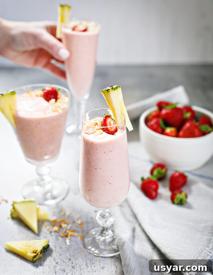 Strawberry Pineapple Smoothie Recipe 4 woman setting 3 glasses of Strawberry Pineapple Smoothie on a table next to a bowl of strawberries