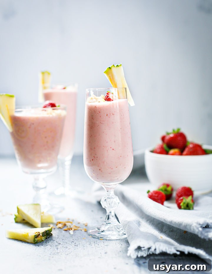 Strawberry Pineapple Smoothie Recipe 5 photo of 3 glasses of Strawberry Pineapple Smoothie next to a bowl of strawberries