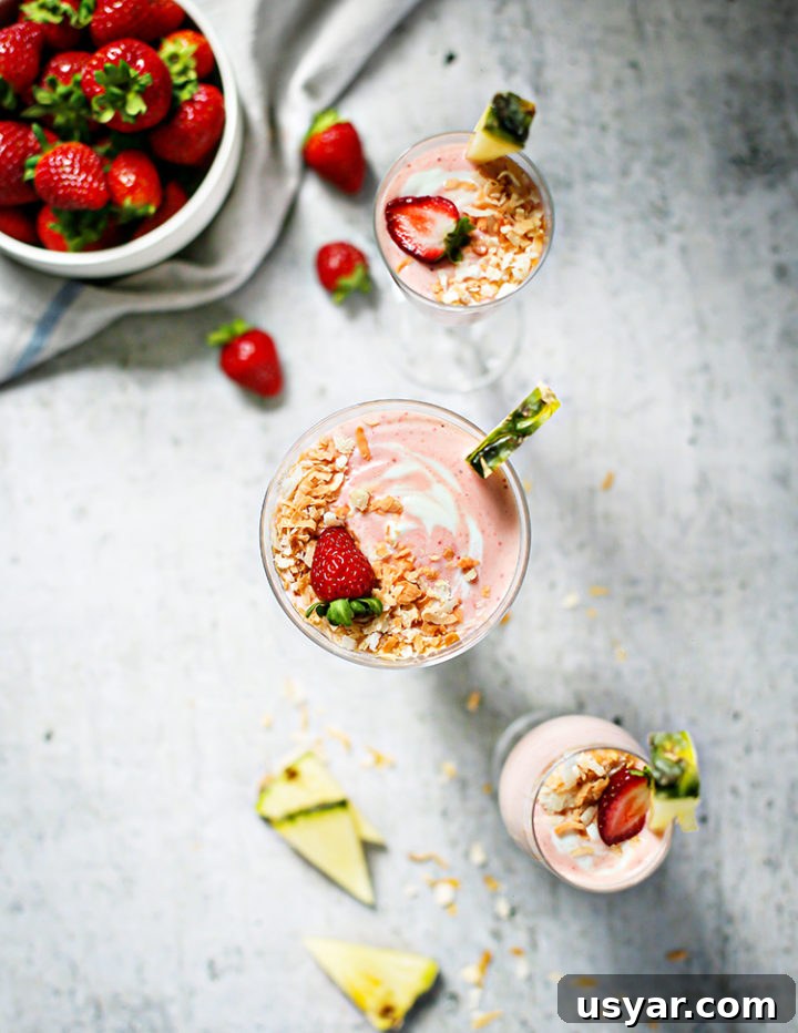 Strawberry Pineapple Smoothie Recipe 6 overhead photo of three glasses of Strawberry Pineapple Smoothie with a bowl of strawberries