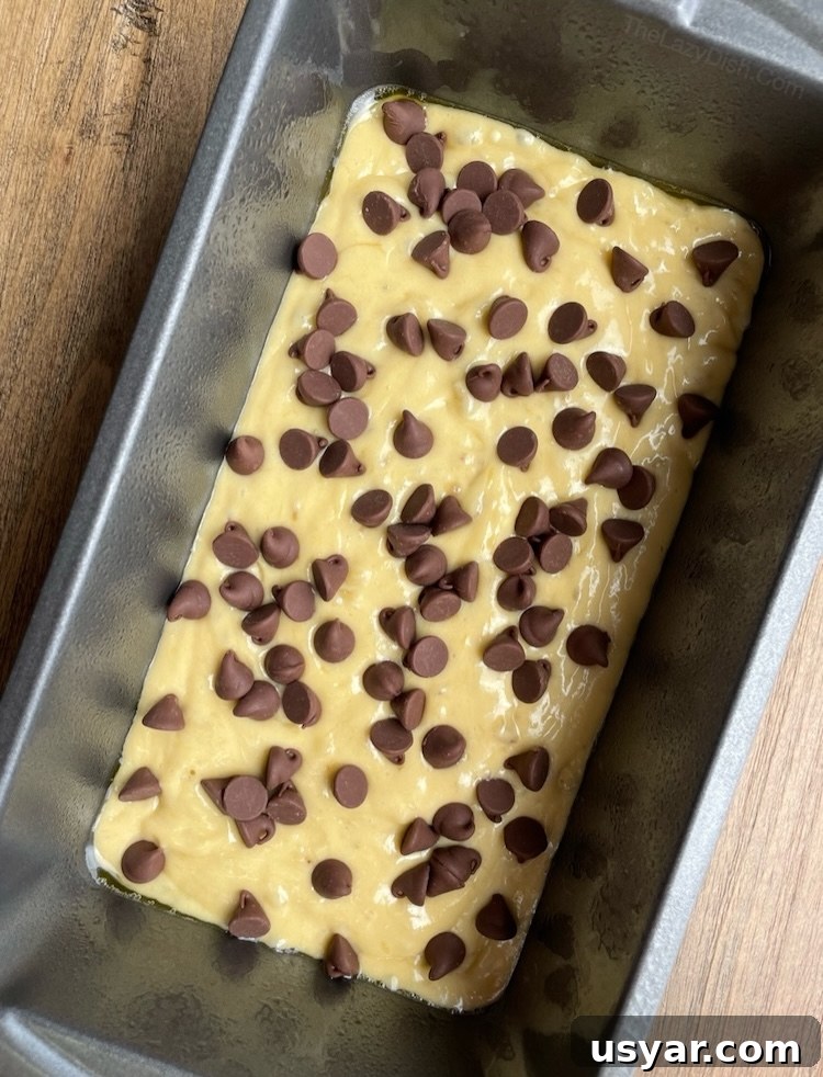 3 Ingredient Cake Mix Banana Bread Recipe 6 Yellow cake mix banana bread in a bread pan with chocolate chips on top, ready for baking.