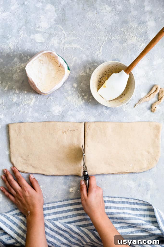 Swedish Cardamom Buns Recipe 8 overhead shot of a person using a pizza cutter to slice the dough