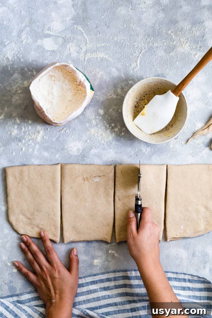 Swedish Cardamom Buns Recipe 9 top view of a person slicing the dough with pizza cutter