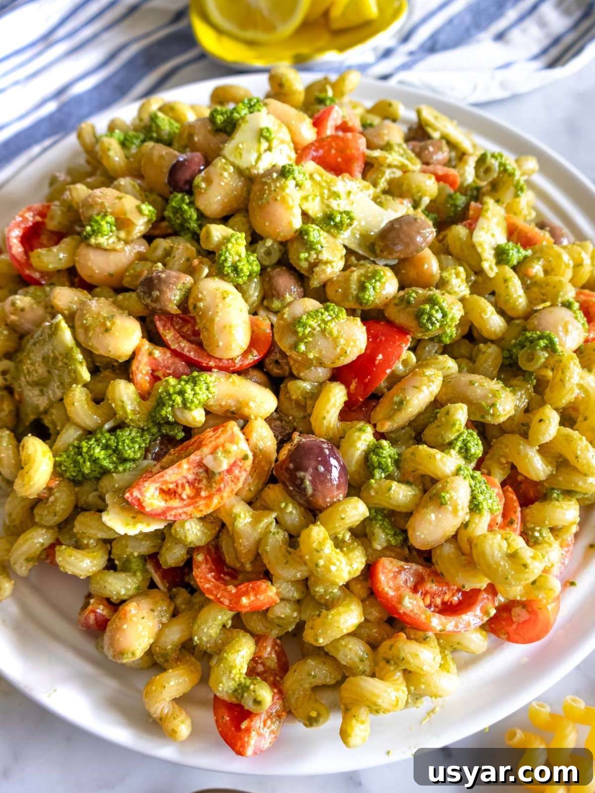Pesto Pasta Salad with Marinated Butter Beans Recipe 3 Finished pesto pasta salad with marinated butter beans close up with parmesan and tomatoes.