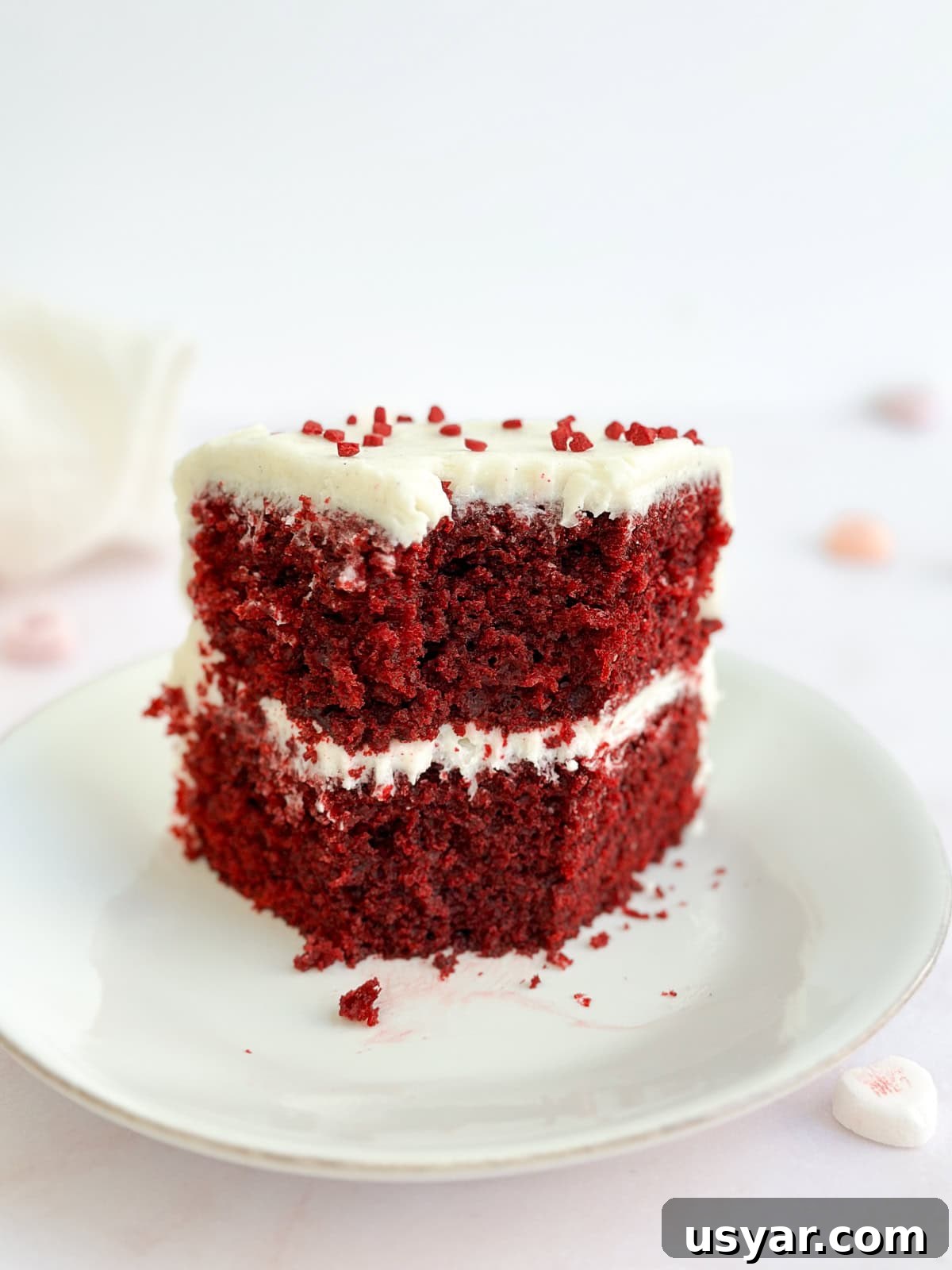 Mini Red Velvet Cake with Cream Cheese Frosting 10 a slice of cake standing up on a plate with a bite missing.