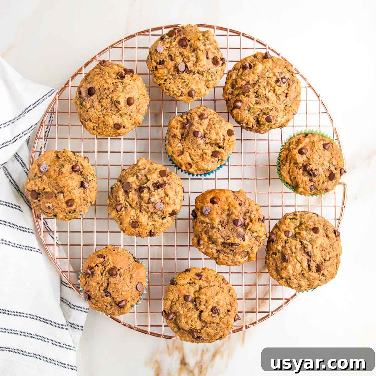 Zucchini muffins with chocolate chips cooling on a wire rack.