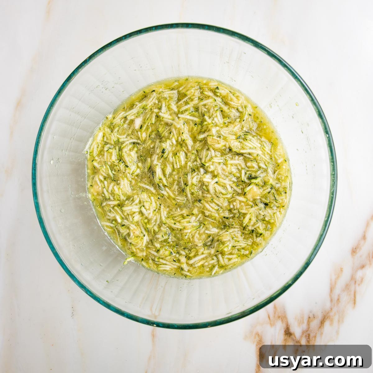 Mixed up wet ingredients for muffins, including shredded zucchini.