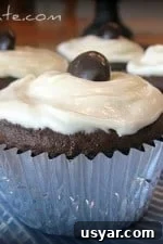 Four Chocolate Fudge Junior Mint Cupcakes topped with frosting and a junior mint wrapped in a silver cupcake liner.