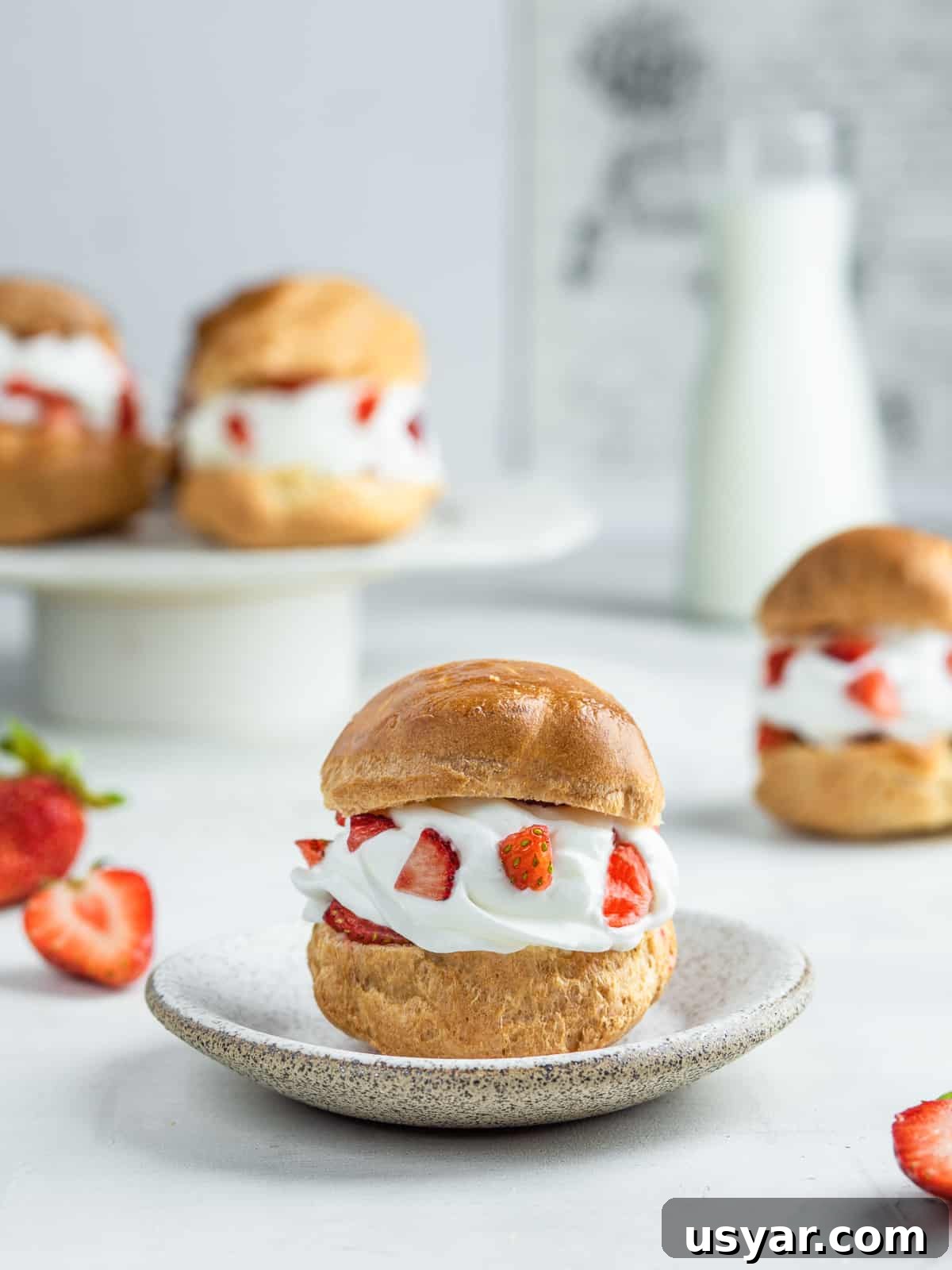 Shu Cream Japanese Cream Puffs Recipe with Custard Filling 5 Japanese cream puffs with cream and fresh strawberries on a plate and a cake stand