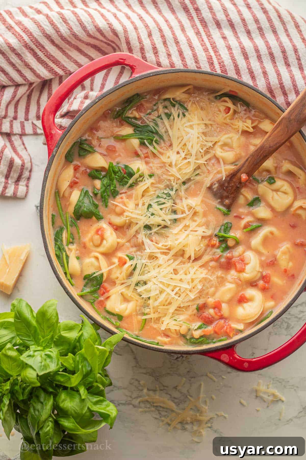 Tuscan Tortellini Soup with Tomatoes and White Beans 2 Tortellini tomato soup in pot with wooden spoon and basil.