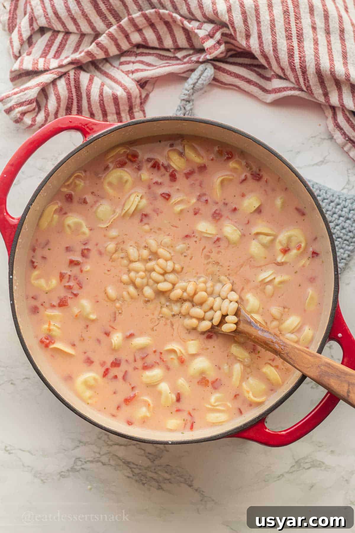 Tuscan Tortellini Soup with Tomatoes and White Beans 6 White beans in soup pot with wooden spoon.