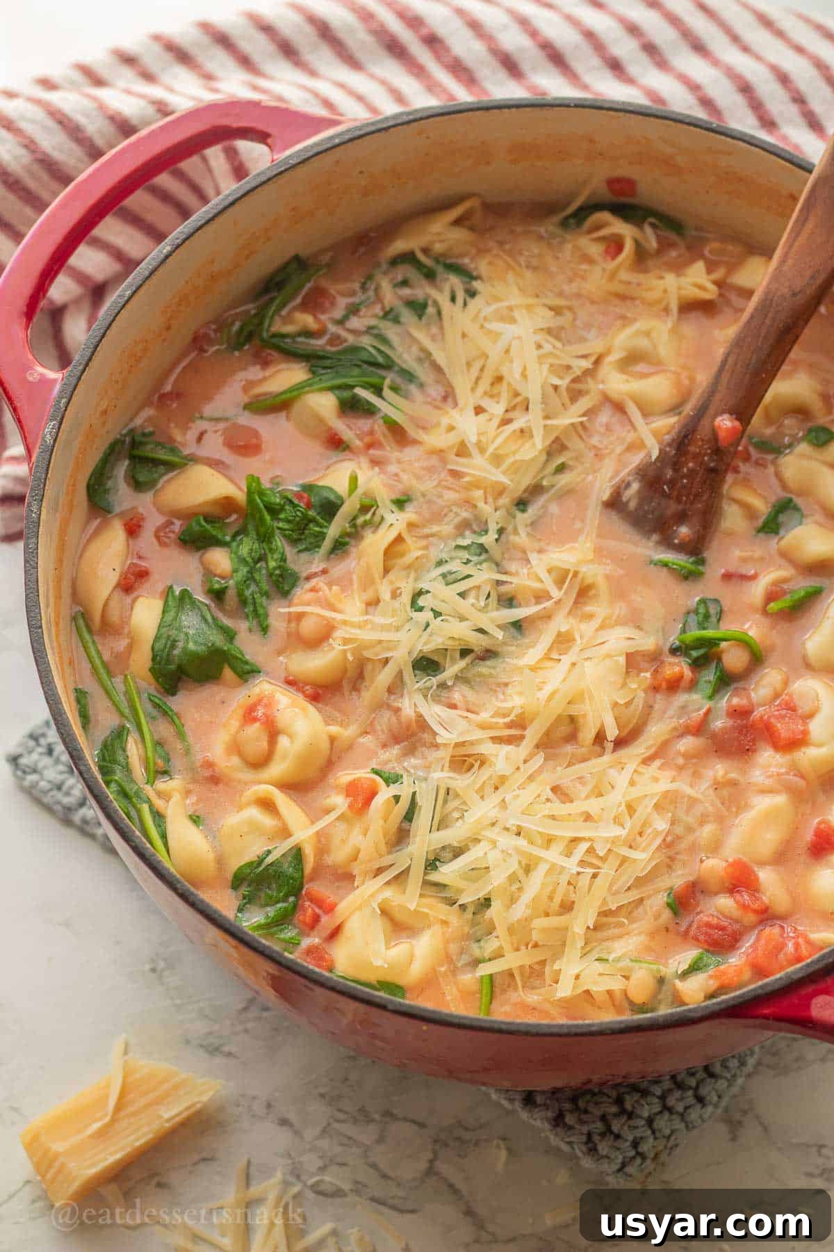 Tuscan Tortellini Soup with Tomatoes and White Beans 8 Tortellini tomato soup in pot with wooden spoon.