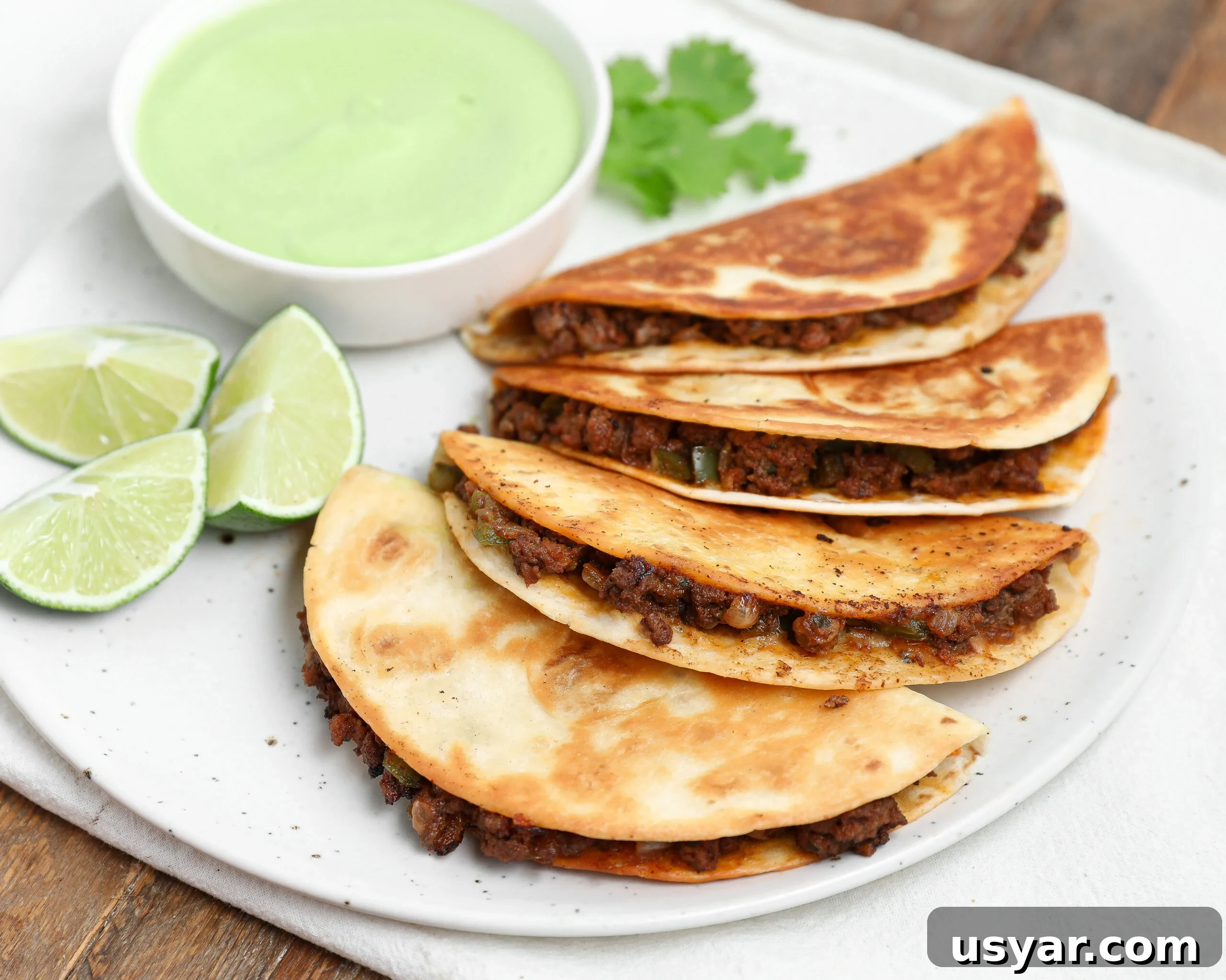 Plated Cheesy Crispy Beef Tacos with Avocado Cilantro Sauce