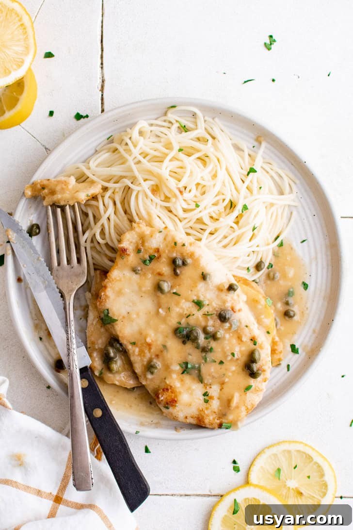 Top down view of chicken piccata with pasta on a plate.