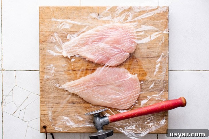 Chicken breast being pounded thin.