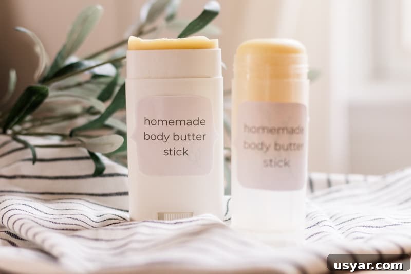 Two body butter sticks on white and black stripe towel.