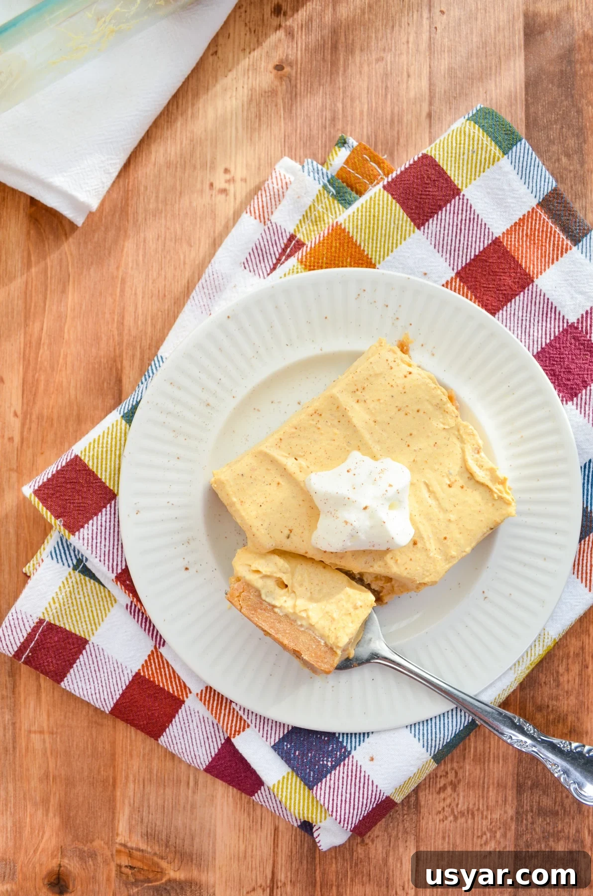 A slice of no bake pumpkin cheesecake bars, on a colorful napkin