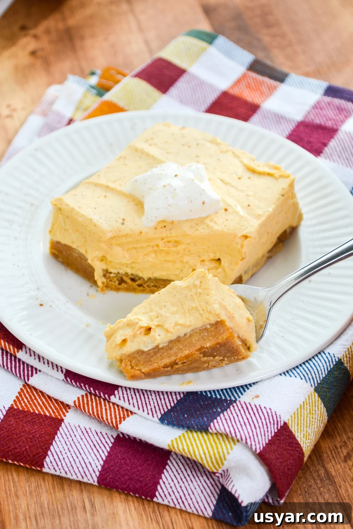 A fork taking a portion of some pumpkin cheesecake bars.