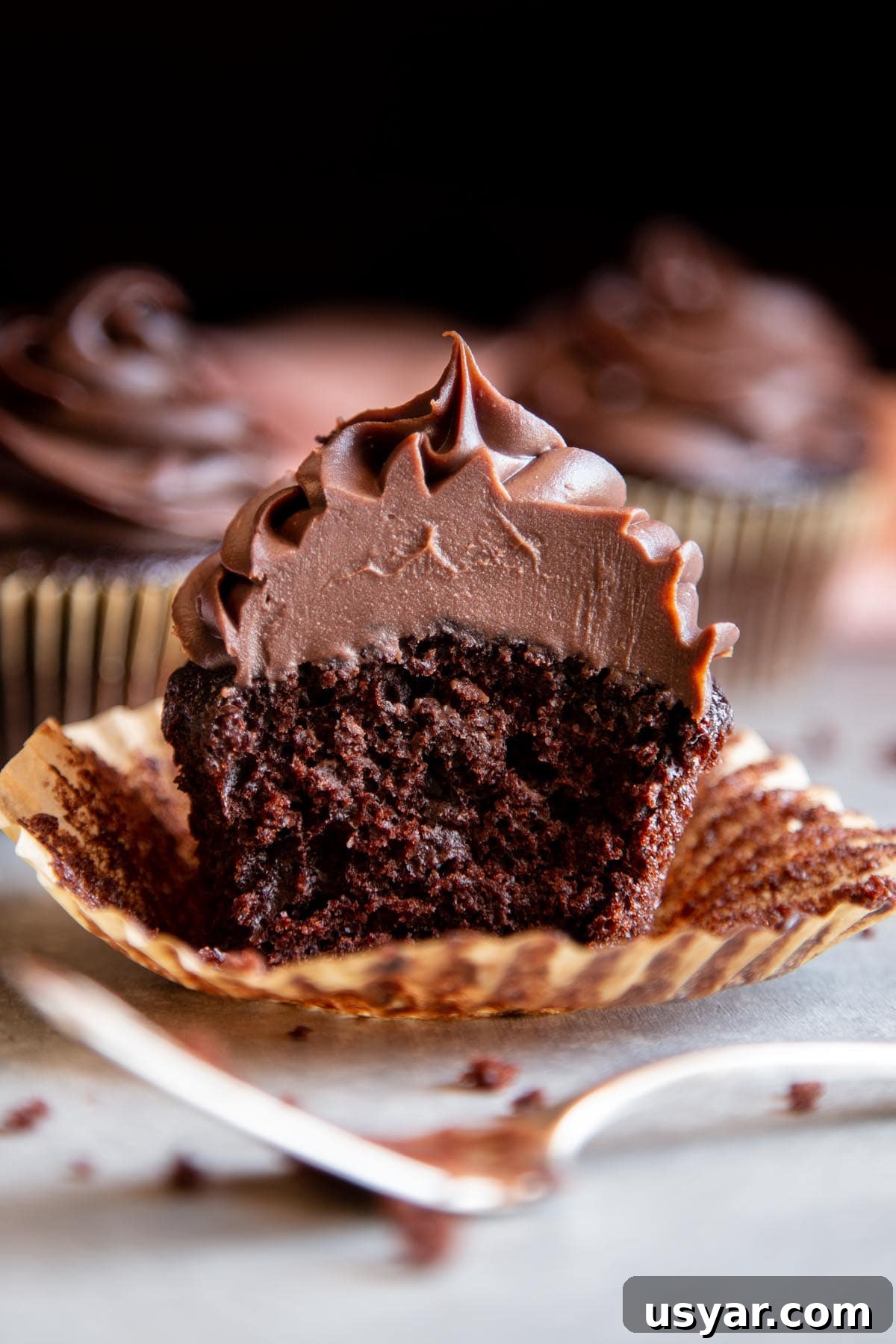 2-Ingredient Chocolate Ganache Frosting Recipe 2 Chocolate ganache frosting on a chocolate cupcake split in half.