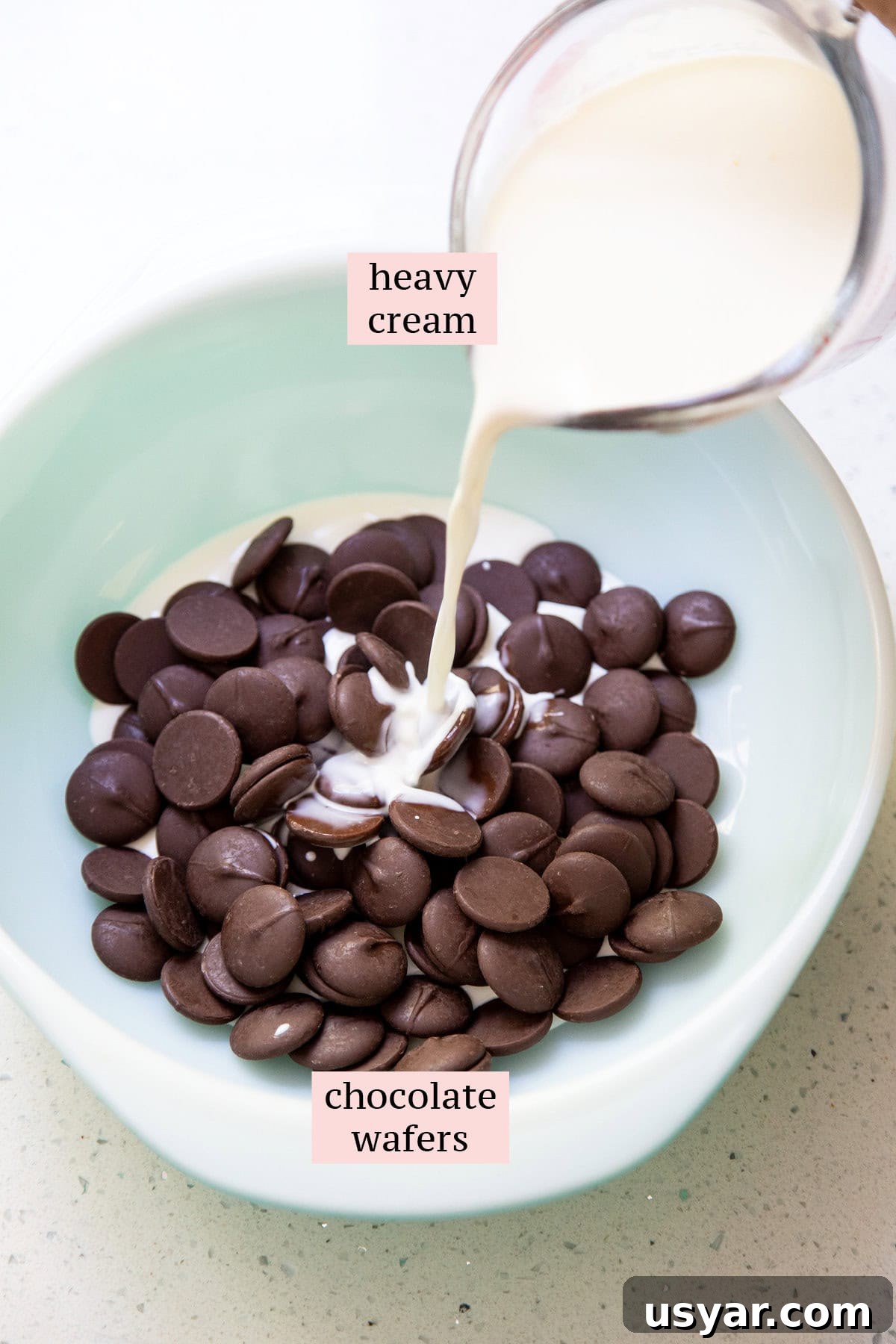 2-Ingredient Chocolate Ganache Frosting Recipe 3 Heavy cream in a measuring cup is pouring into a bowl of chocolate.