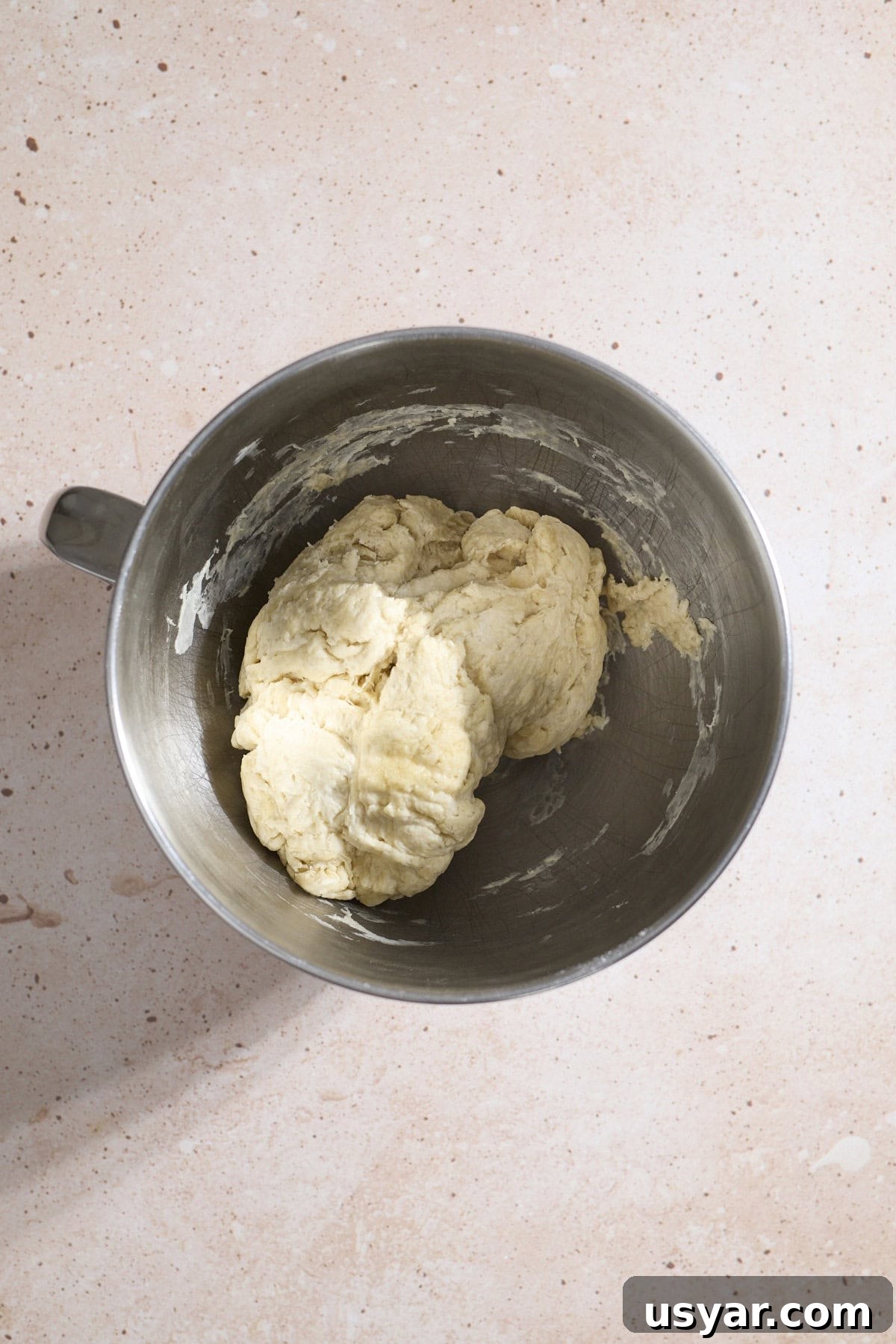 Shaggy dough in the bowl of a stand mixer.