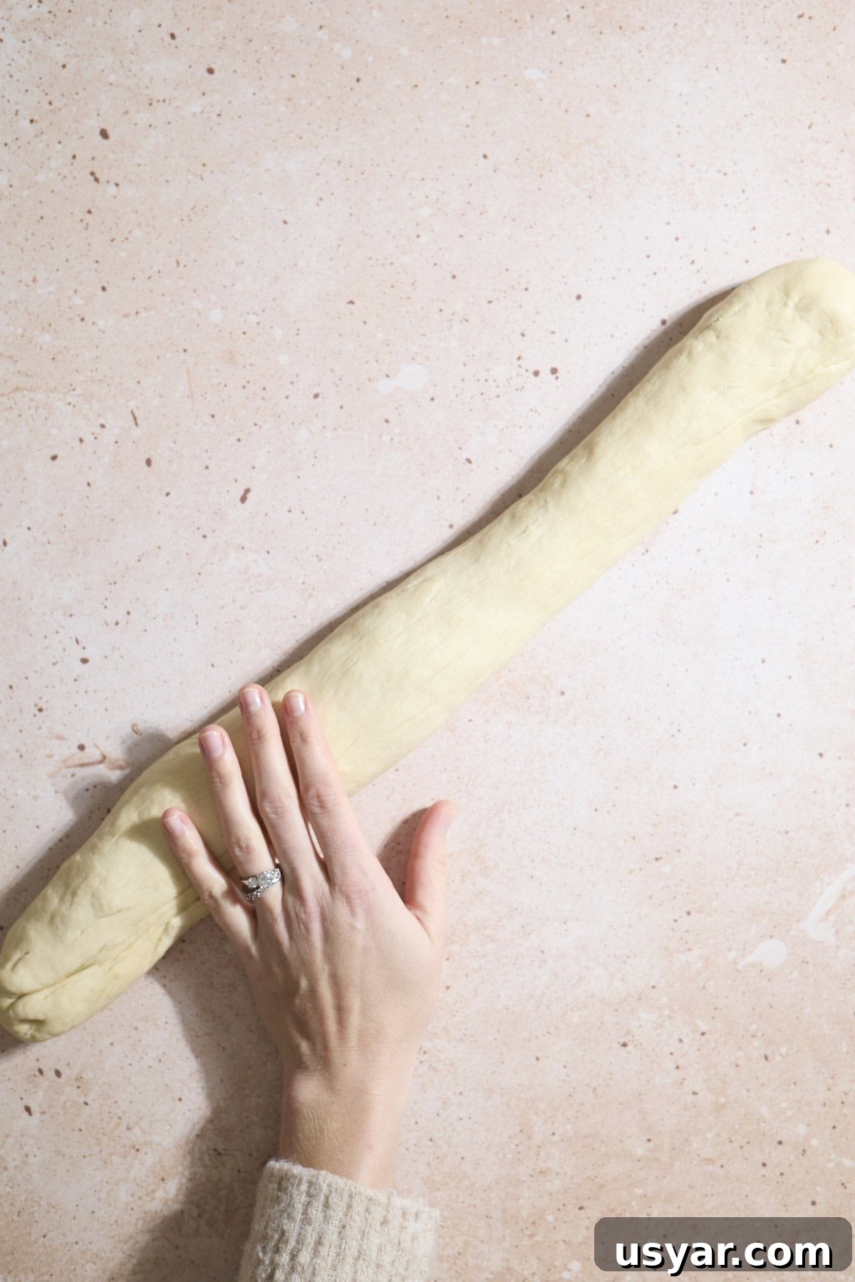 Dough being rolled into a long log.