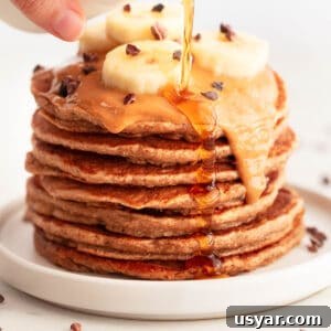 Vegan banana pancakes topped with peanut butter, chocolate chips, and sliced bananas.
