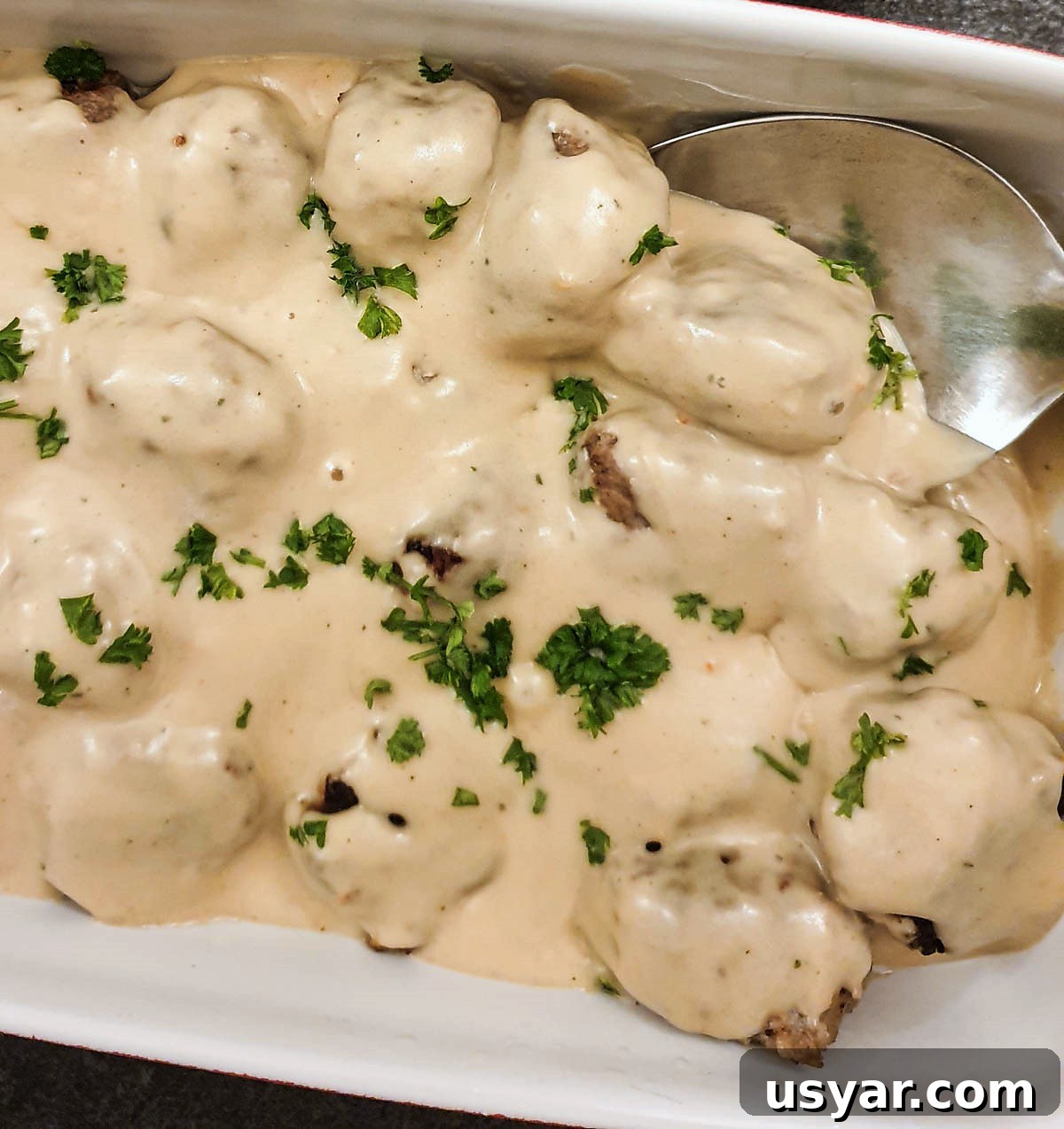A dishful of meatballs covered with mustard sauce.