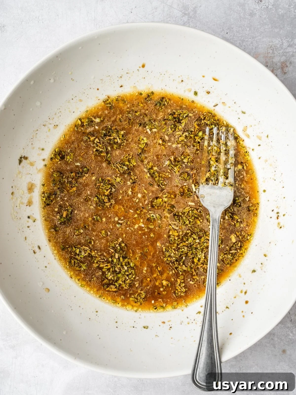 Authentic Middle Eastern Beef Shish Kebab Recipe with Sides 5 Bowl with the shish kebab marinade including olive oil, lemon juice, pomegranate molasses, oregano, garlic, salt and pepper.
