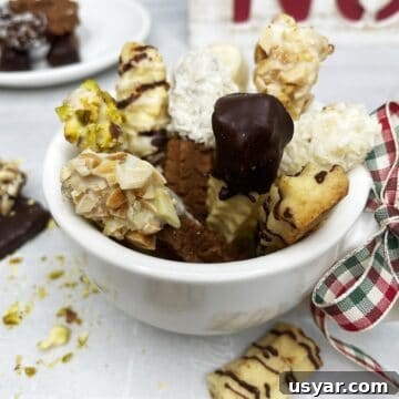 Dipped spritz cookies in a cup with the rest of the cookies in the background.