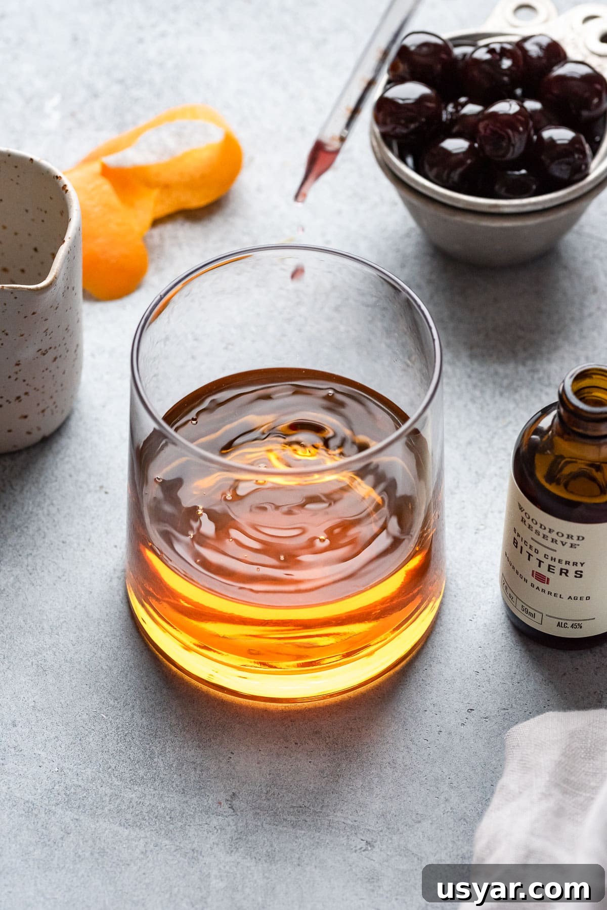Maple Old-Fashioned Bourbon Cocktail Recipe and Serving Tips 4 dropping bitters into cocktail