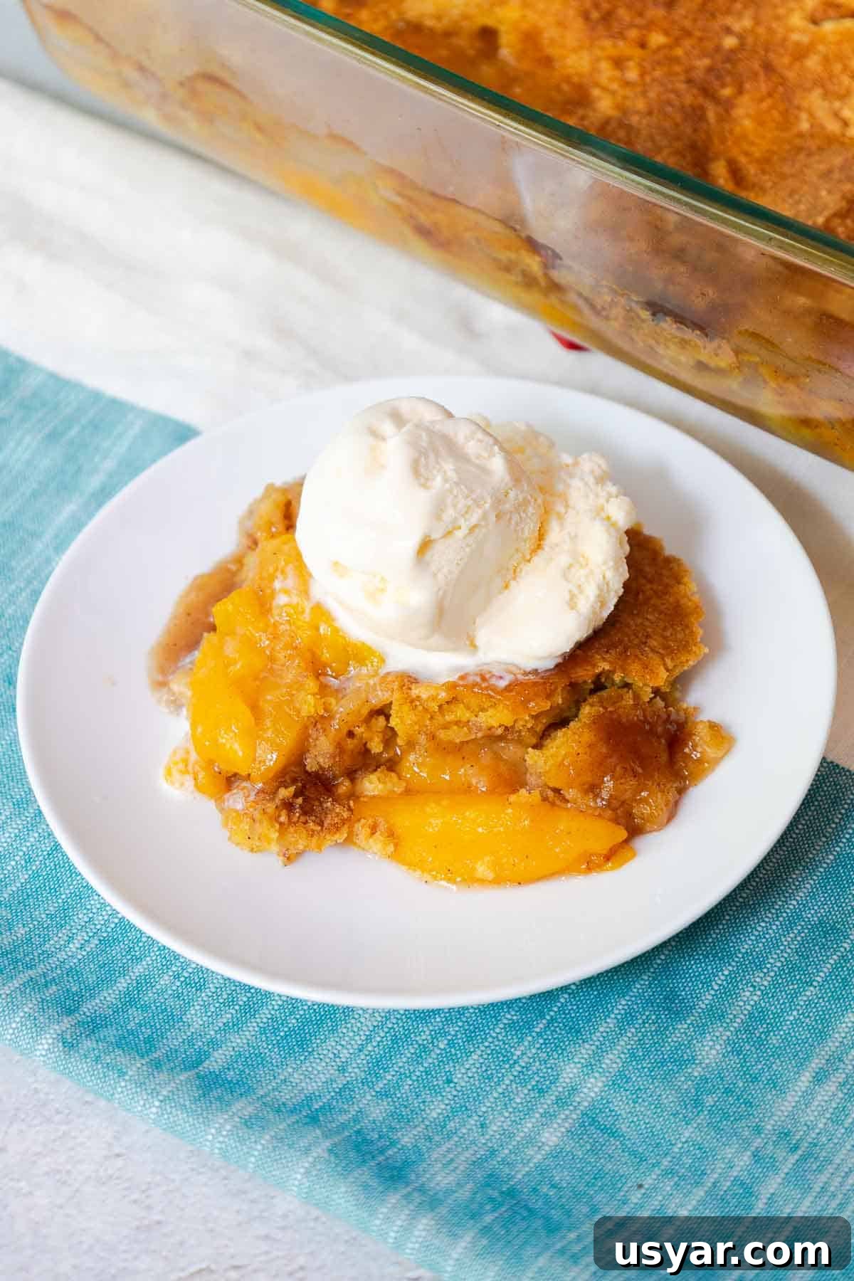 Cake Mix Peach Cobbler with Canned Peaches 2 Peach cobbler topped with a scoop of vanilla ice cream.