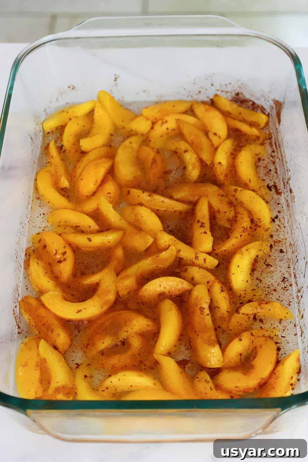 Cake Mix Peach Cobbler with Canned Peaches 5 Sliced peaches in a baking dish sprinkled with cinnamon.