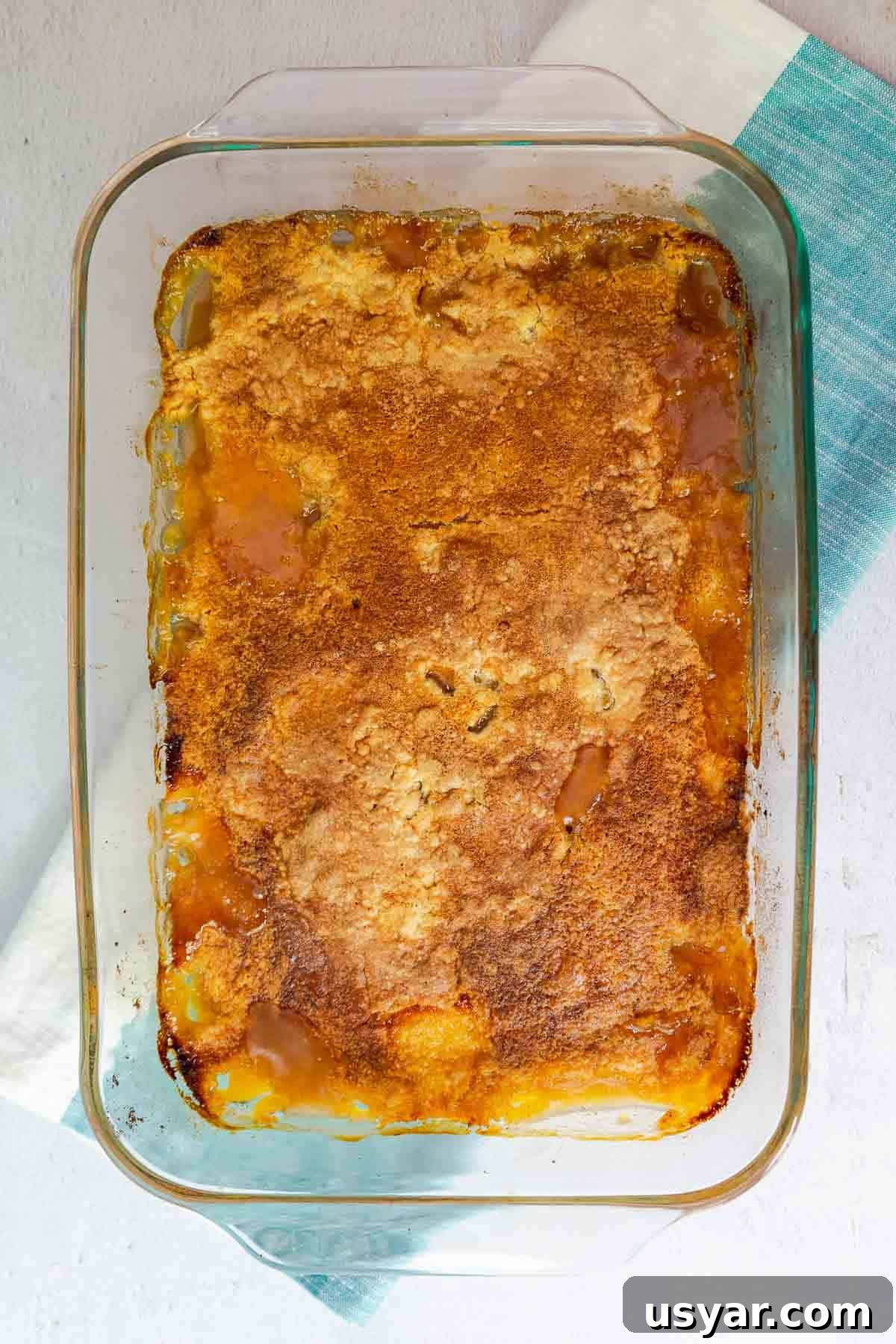Cake Mix Peach Cobbler with Canned Peaches 8 A baked peach cobbler with a golden brown top in a glass dish.