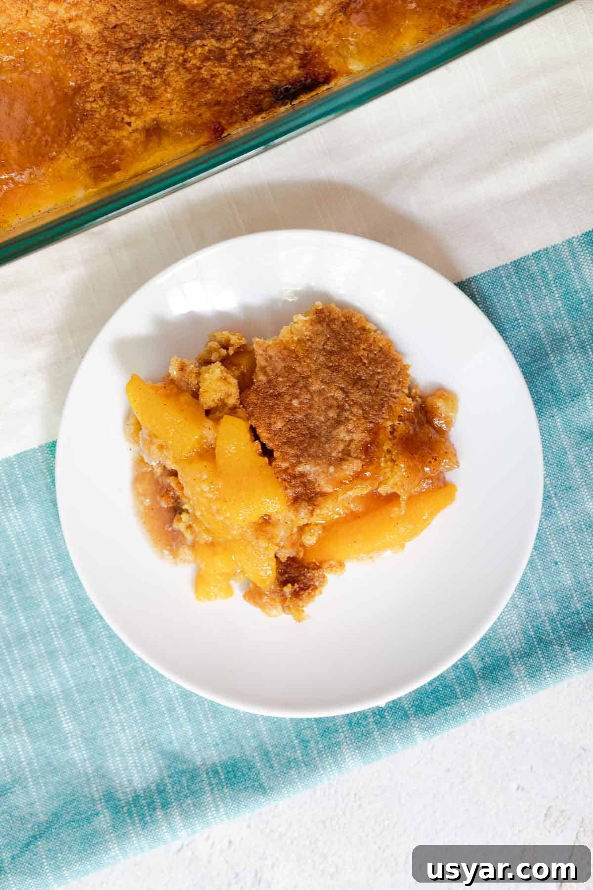 Cake Mix Peach Cobbler with Canned Peaches 9 A serving of peach cobbler on a small plate.