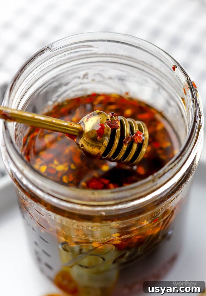 hot honey in a glass jar with a ribbed brass honey dipper.