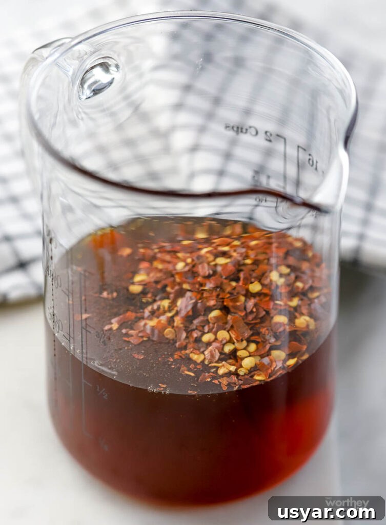 a glass measuring cup with honey and red pepper flakes. 