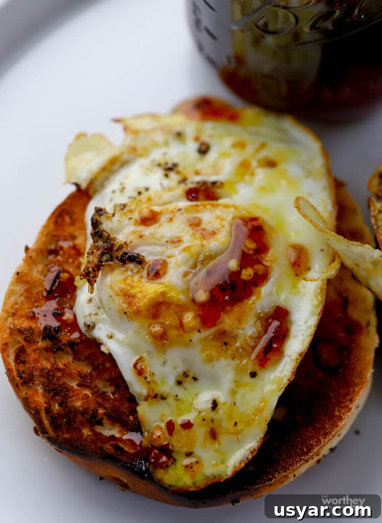 a bagel topped with a fried egg with a drizzle of hot honey on top. 