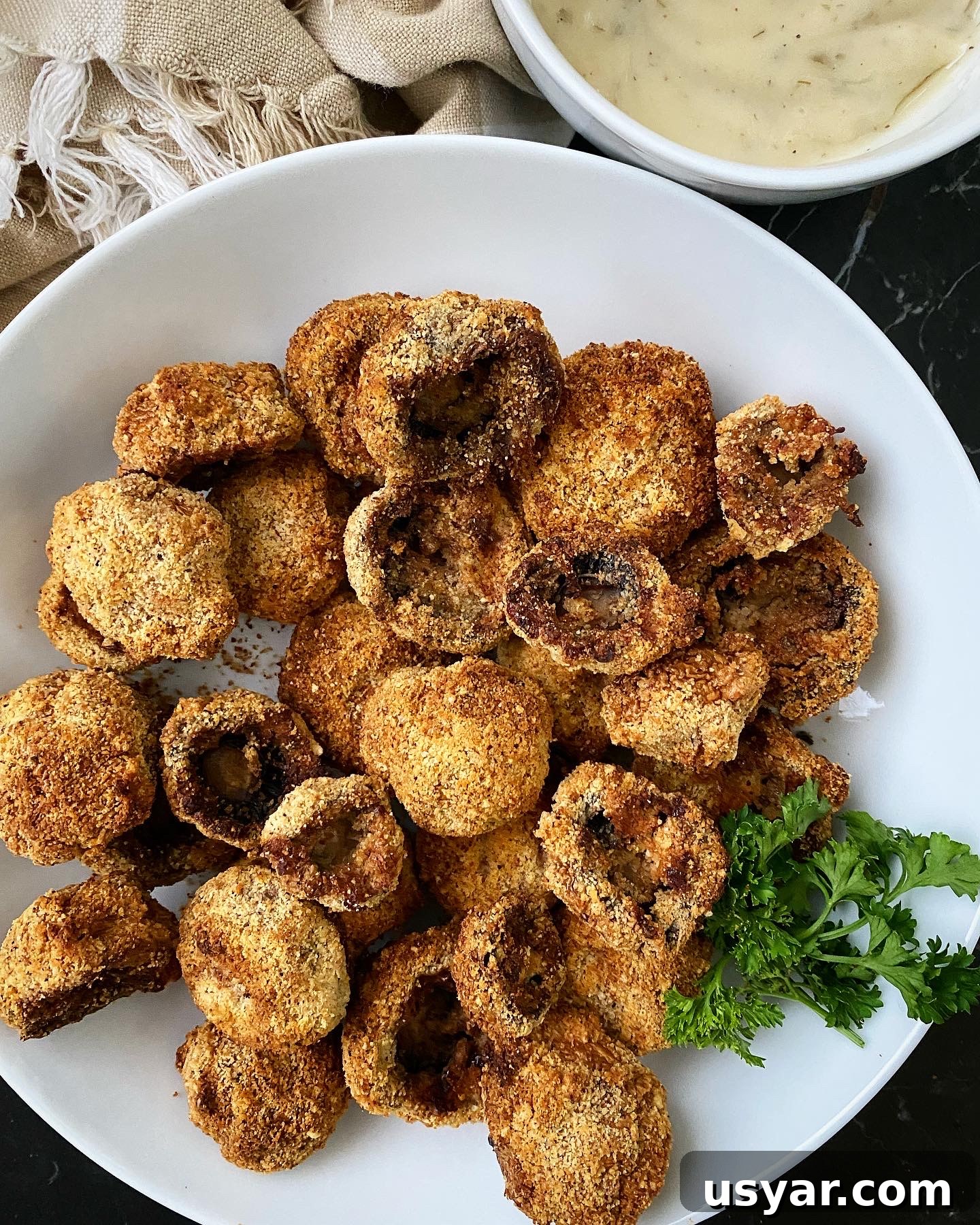 cooked air fryer fried mushrooms with a bowl of white dipping sauce