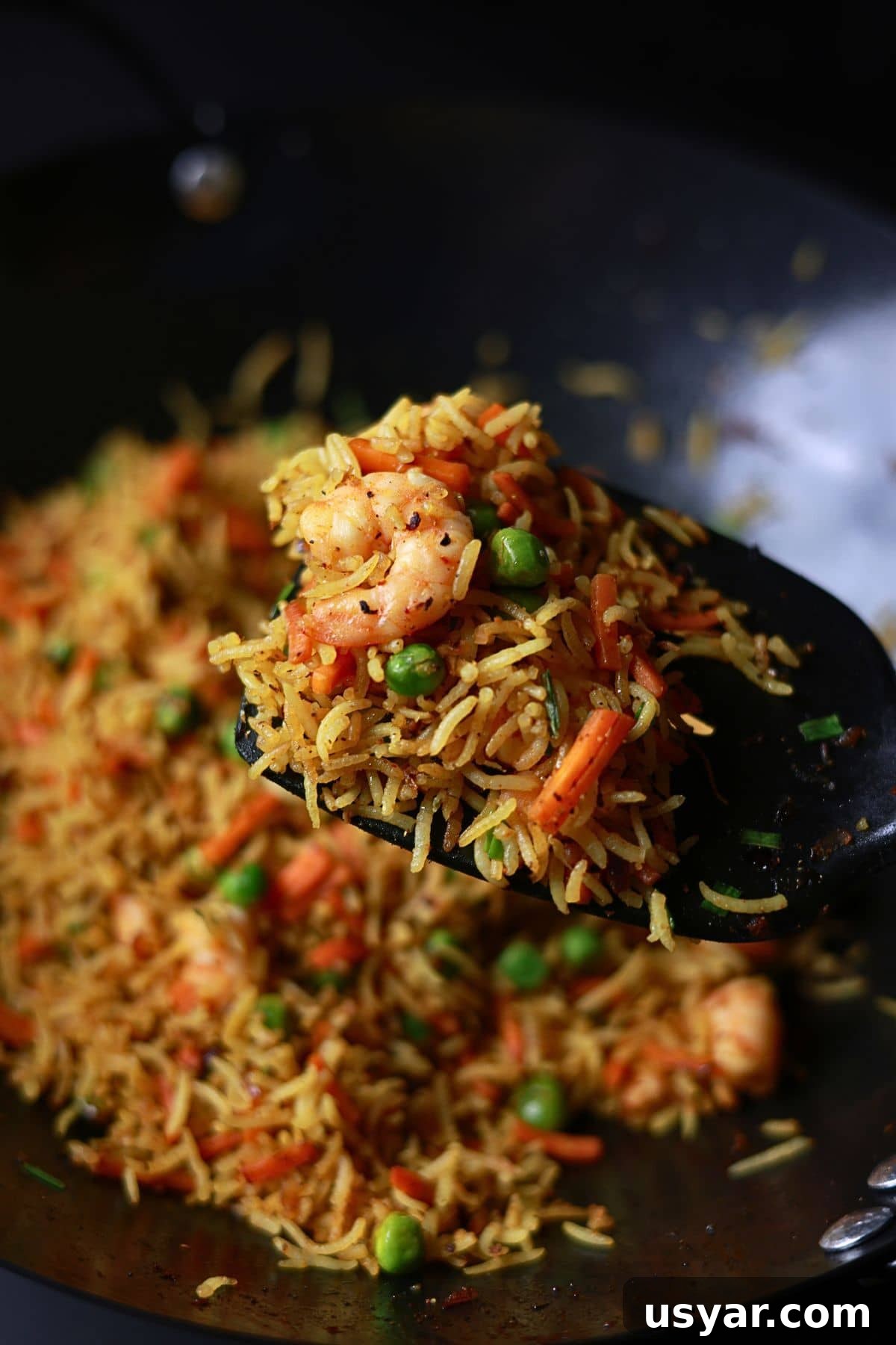 Quick Shrimp Curry Fried Rice Recipe 5 Curry fried rice is held on a spatula inside the wok.