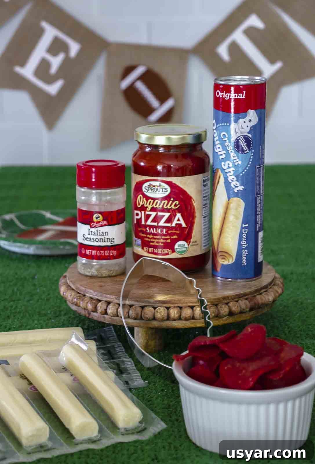 Game Day Mini Football Pizzas with Crescent Roll Dough 3 Ingredients to make mini football pizzas on fake grass.