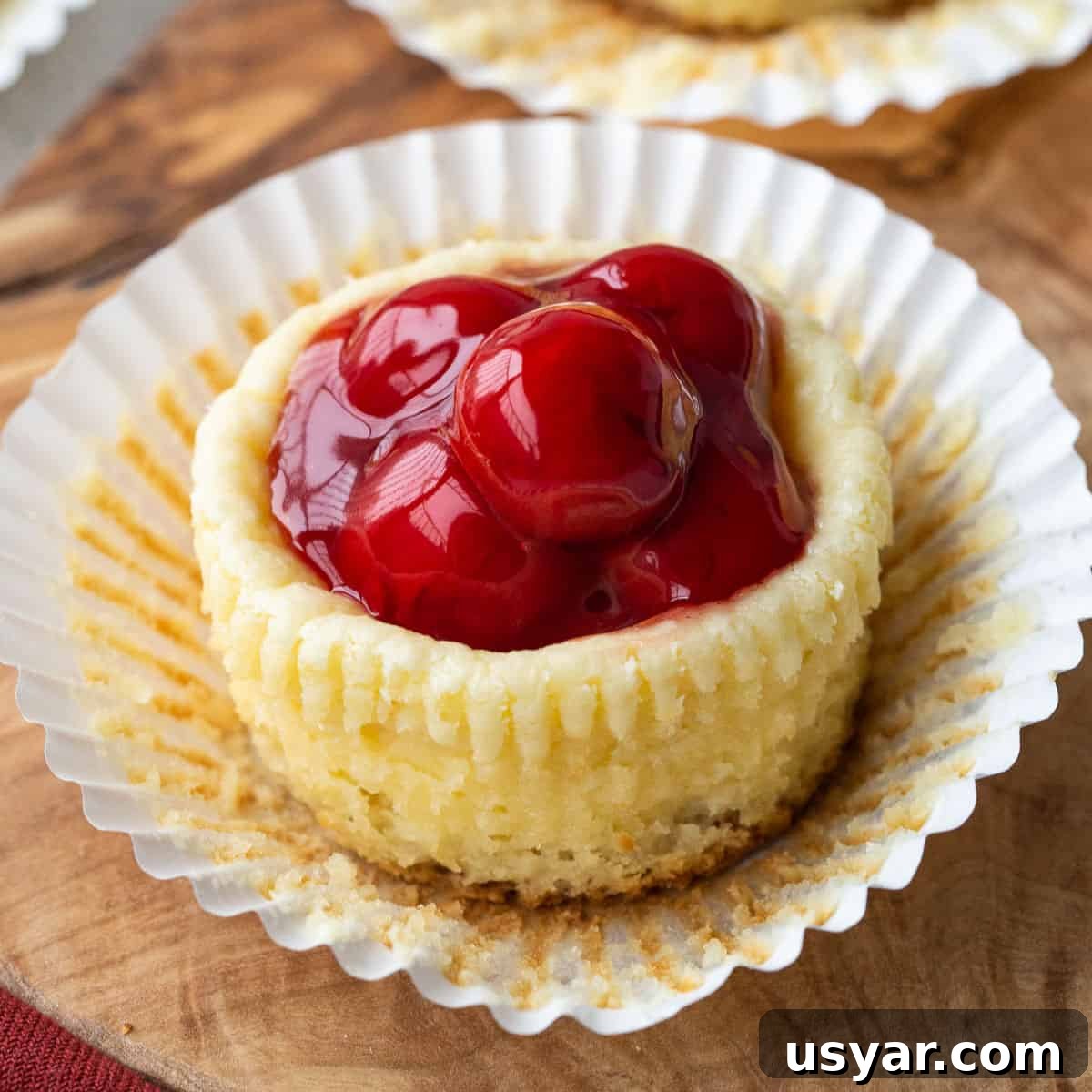 Mini Cherry Cheesecakes with Graham Cracker Crust 2 mini cherry cheesecake in a cupcake liner.