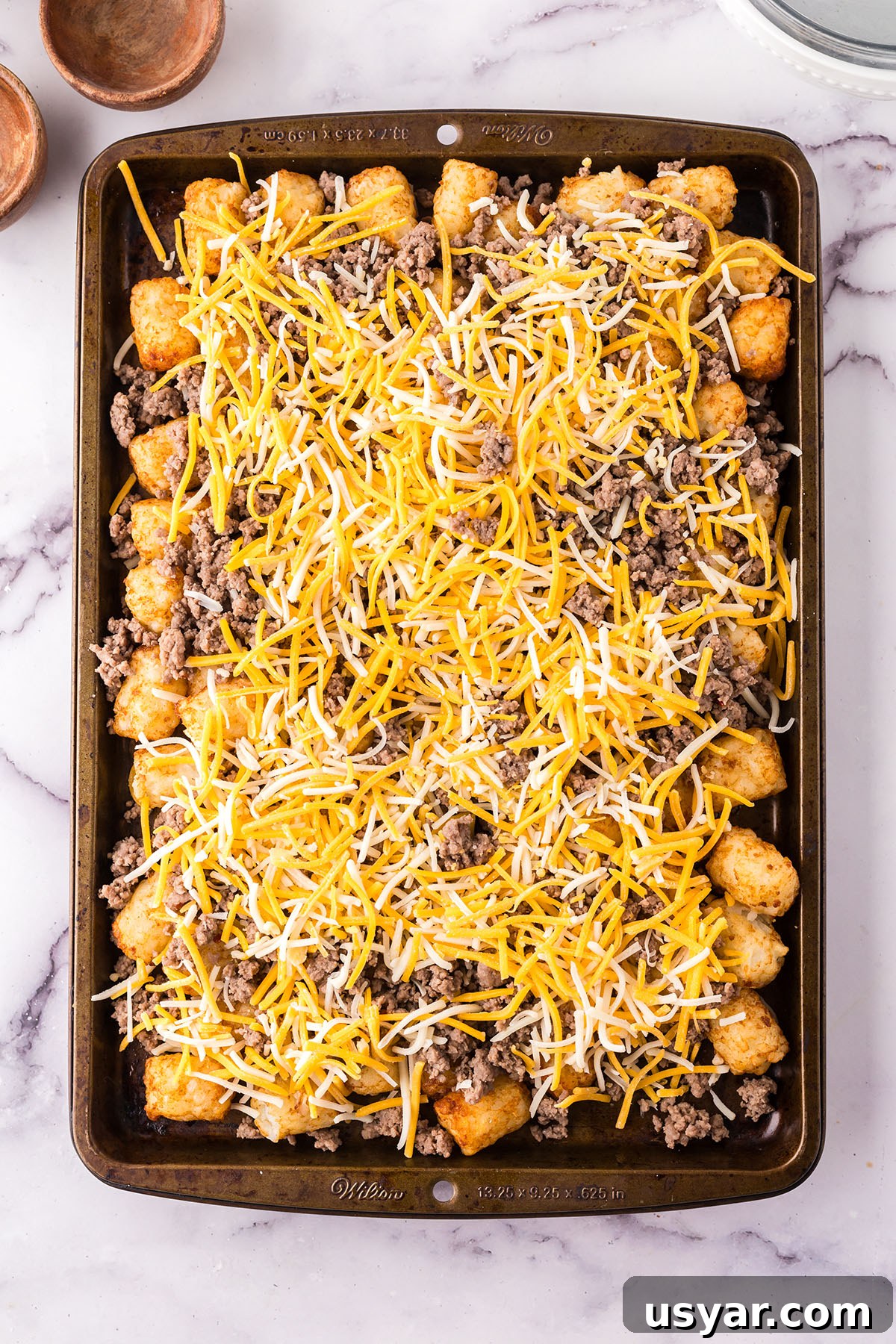 Mexican Totchos: Tater Tot Nachos with Pico and Cheese 6 Mexican Totchos are layered on baking sheet ready for the oven.