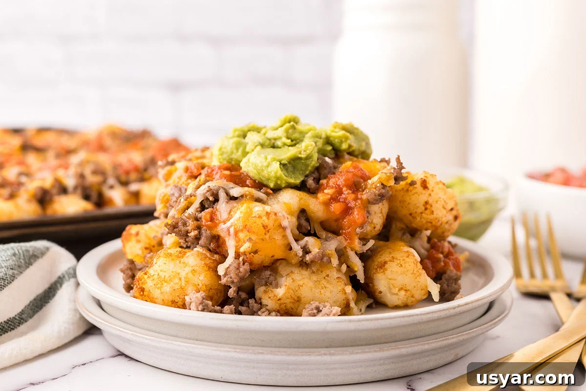Mexican Totchos: Tater Tot Nachos with Pico and Cheese 8 A serving of Mexican Totchos topped with guacamole on a plate.