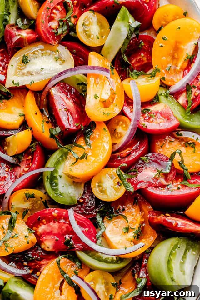 Heirloom Tomato Salad with Basil Vinaigrette 4 top view close up of wedges of heirloom tomatoes topped with slices of red onions and crumbled feta cheese
