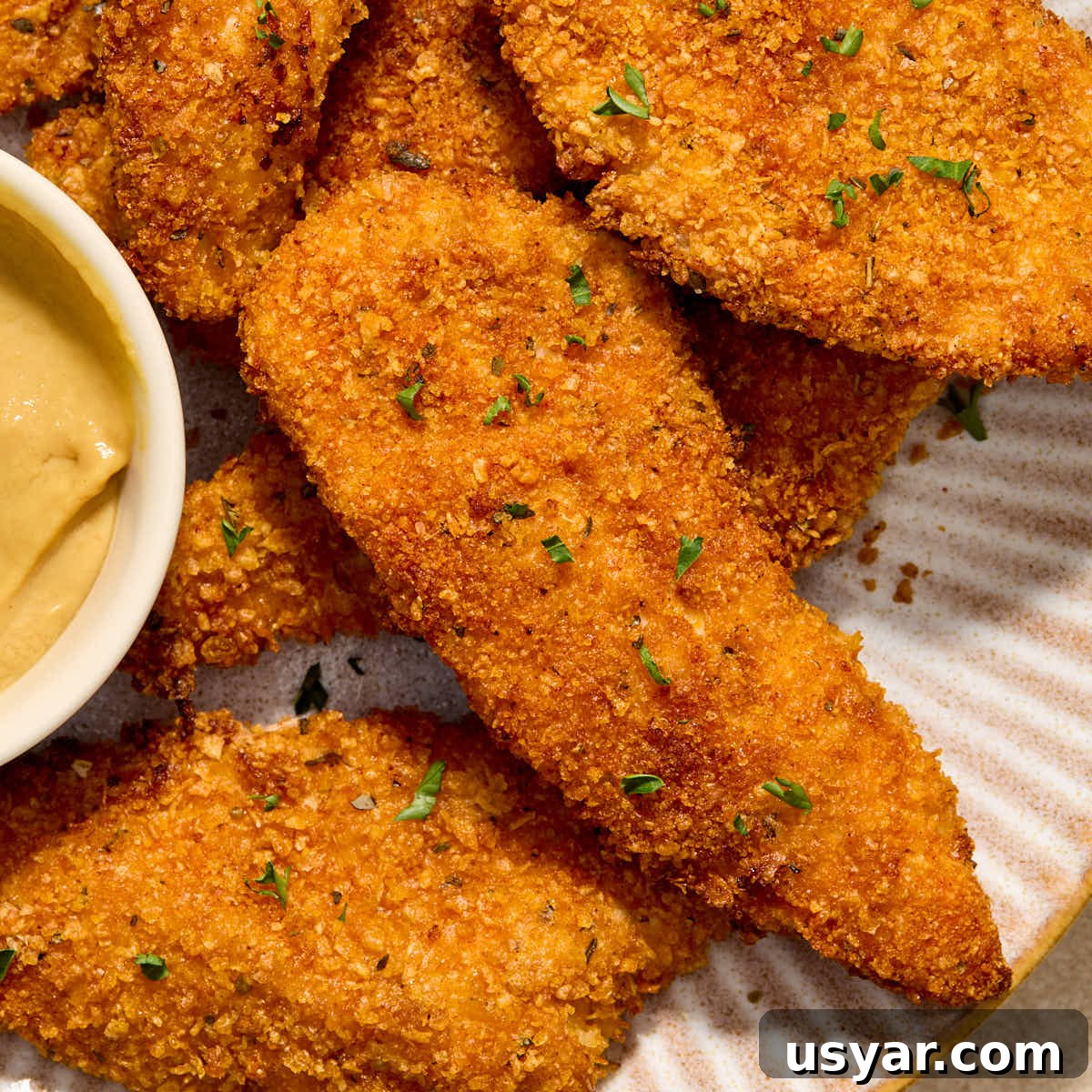Close up view of air fryer cornflake chicken strips on a plate.