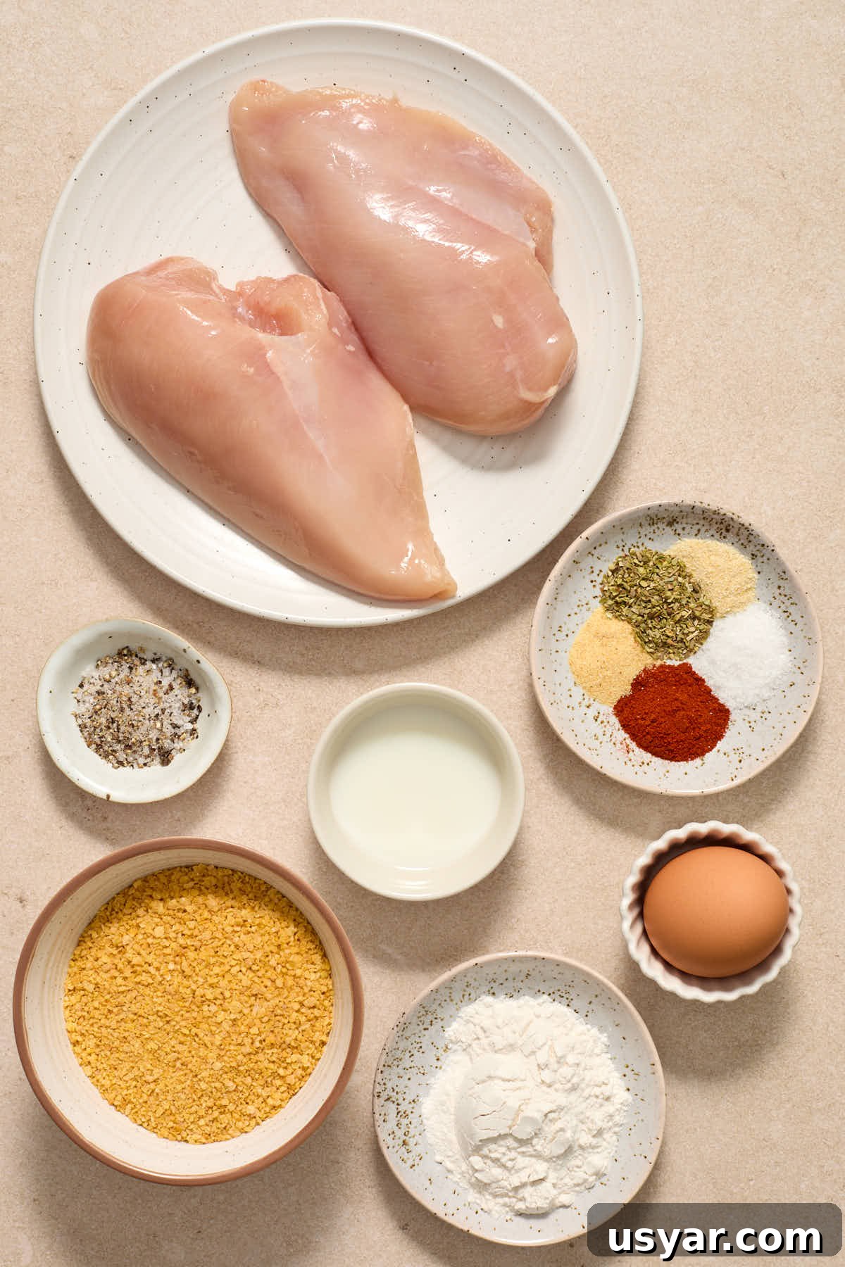 Ingredients to make cornflake chicken arranged in separate dishes.